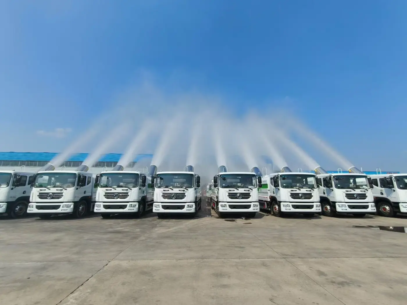 Fleet of Dongfeng water tanker trucks spraying with fog cannons for dust control